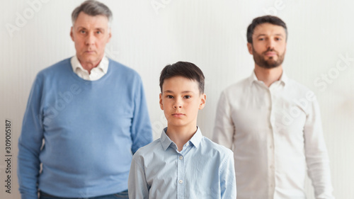 Serious Boy, Father And Grandfather Standing Over White Background, Panorama