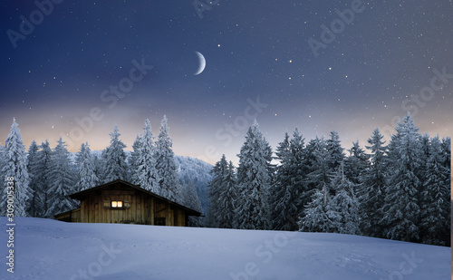 Beleuchtete Holzhütte in einer Winternacht