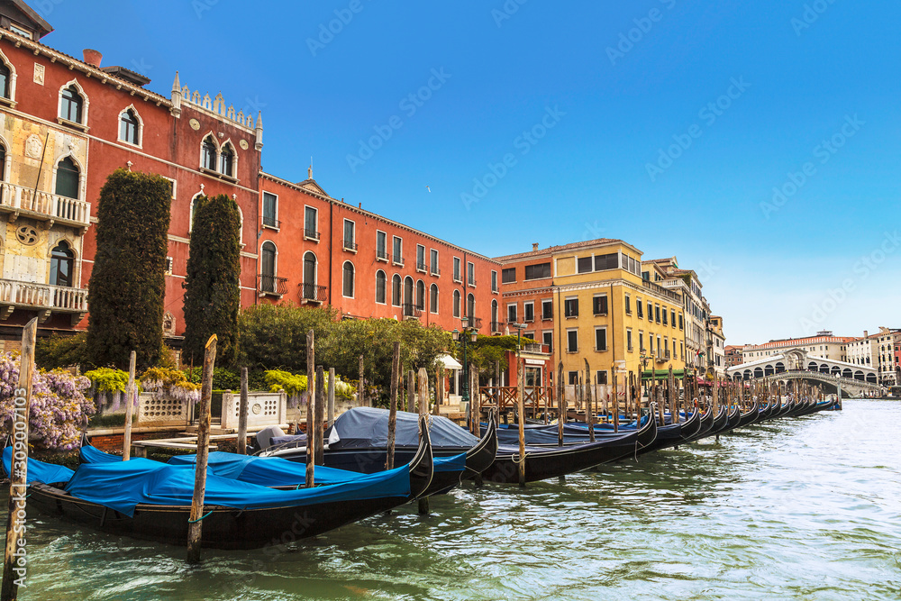 View of the Grand canal, pier with gondolas and Rialto bridge on the horizon, Venice, Italy