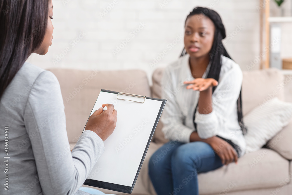 Psychologist taking notes during therapy session with her emotional female patient Psychologist taking notes during therapy session with her emotional female patient