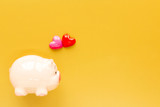A piggy bank and red and pink heart put on the brown background and copy space for ad text, the saving for loved one and planned investment in the future concept.
