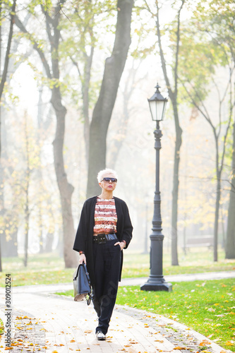 stylish blond woman in autumn park