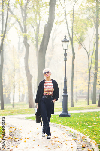 stylish blond woman in autumn park
