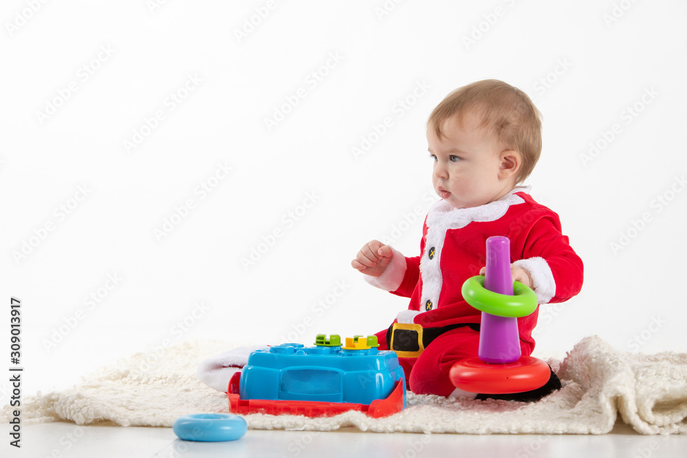 baby dressed as Santa Claus sitting on the floor playing with toys baby dressed as Santa Claus sitting on the floor playing with toys