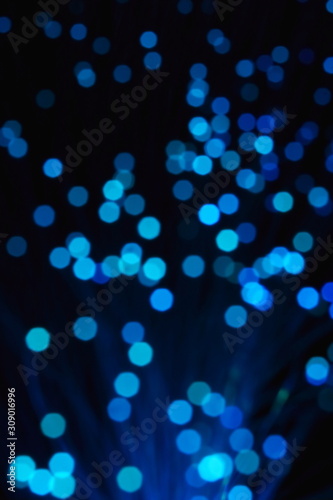 New Year and Christmas color illumination. The illusion of a salute explosion. The quirks of light fiber optic lamp. Blurry circles, bokeh on a dark background. Big explosion.