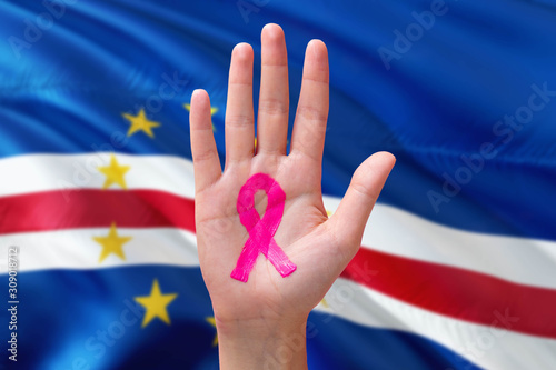 Cape Verde awareness concept. Close-up awareness ribbon painted on palm on national flag background. October Pink day and world cancer day.