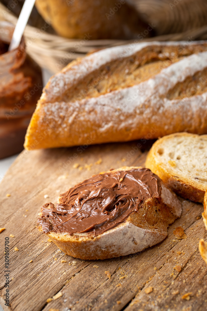 Fresh Homemade Sliced French Baguette Bread topped with chocolate On Wooden Bread Board