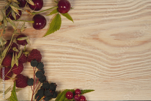 red currant, raspberry, cherry, leaves, cereals on a light wood background.room for text.