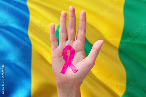 Saint Vincent And The Grenadines awareness concept. Close-up awareness ribbon painted on palm on national flag background. October Pink day and world cancer day.