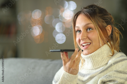 Foto Happy woman using voice recognition on phone in winter