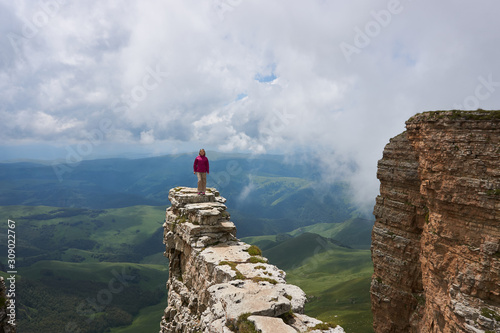 the smiling girl walks along a cliff in the mountains