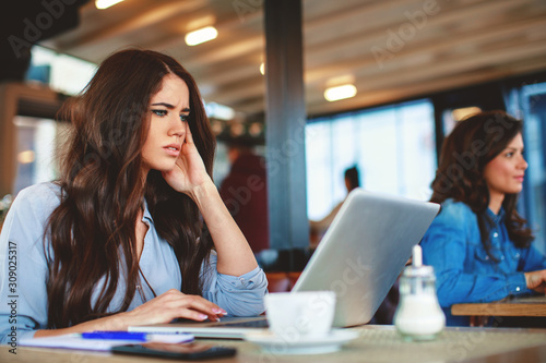 Young worried woman online via a laptop in a cafe