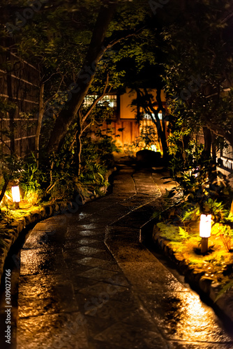 Kyoto  Japan empty street garden in Gion district at night with illuminated white green lanterns on wet road path