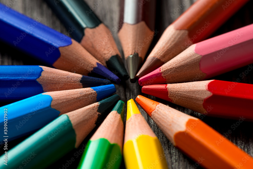 group of colored pencils lie in a circle on a wooden table group of colored pencils lie in a circle on a wooden table