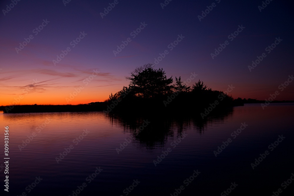 Sunset over Assateague Island over marshes, salt water bay with silhouette