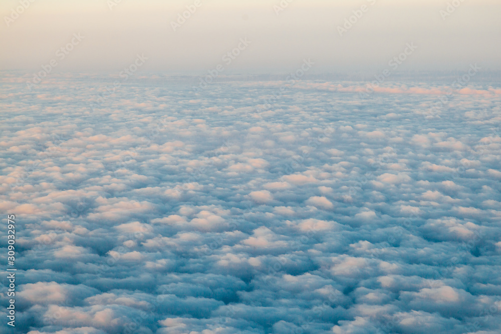 flying above the clouds at sunset landscape from an airplane