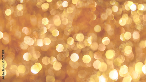 Bright light bokeh on golden background, festive Christmas background_