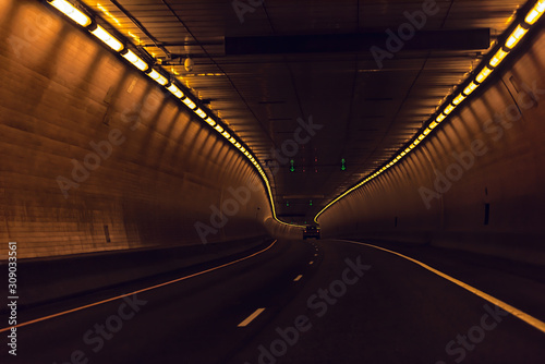 Highway dark road near Glenwood Springs Canyon in Colorado with long exposure of light inside tunnel with orange color and car © Andriy Blokhin
