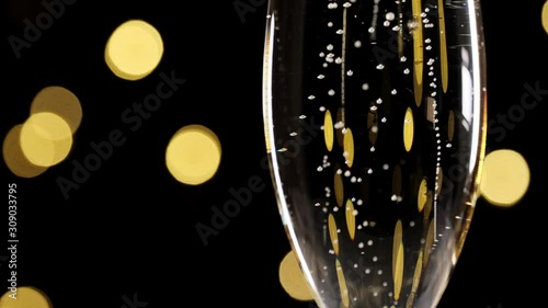 champagne in a glass, concept of new year and Christmas champagne pouring in a glass dark background with beautiful yellowbokeh. champagne pour into a glass. Close up shot. Slow motion photo