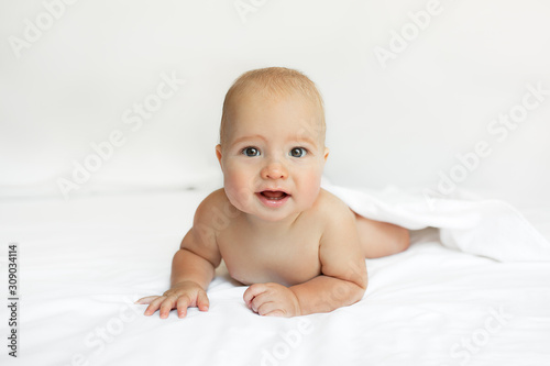 Baby on White background. Adorable two month old baby boy lying on the bad. Concept photo parenthood and motherhood.