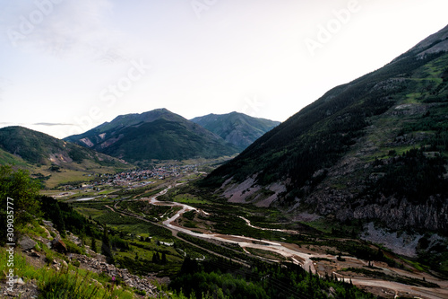 Wide angle aerial view of Silverton, Colorado small town from overlook at morning sunrise in summer with river and dark mountains