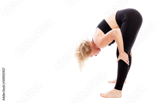 Young woman in black fitness attire doing stretching while standing. Isolated over white background. Space for text.