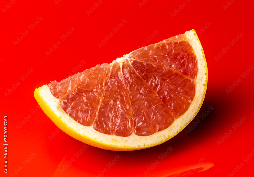 Slice of a red grapefruit isolated on pure red background Slice of a red grapefruit isolated on pure red background