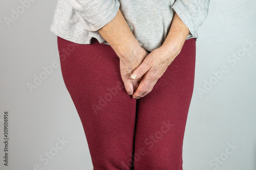 senior woman with hands between legs isolated on White background