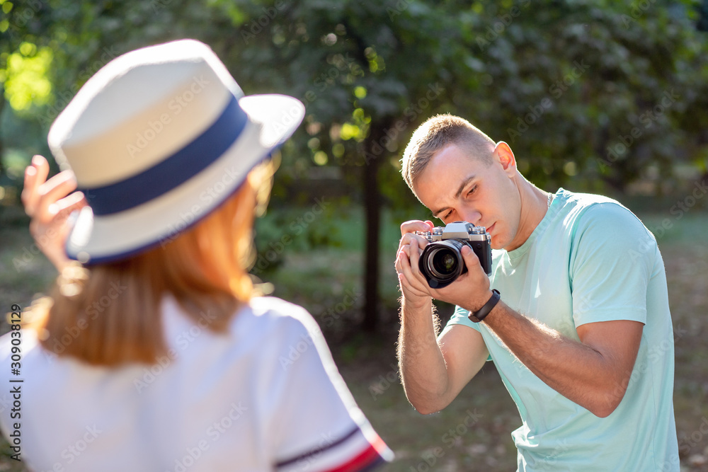Young teenage couple taking pictures of one another outdoors in sunny summer park. Young teenage couple taking pictures of one another outdoors in sunny summer park.