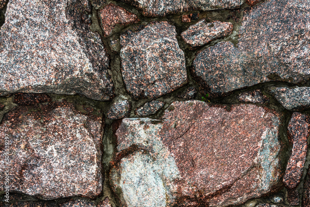 Fototapeta premium old stone wall of uneven granite stones