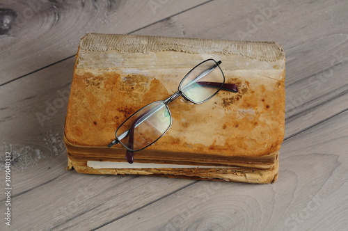 Optical glasses and old book on grey woodboard (ID: 309040332)