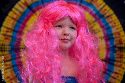 Happy Cute caucasian boy changed clothes at carnival in dress of girl of rainbow color. Pink doll wig. LGBT color background. Education in kindergarten and preschool children. hair coloring