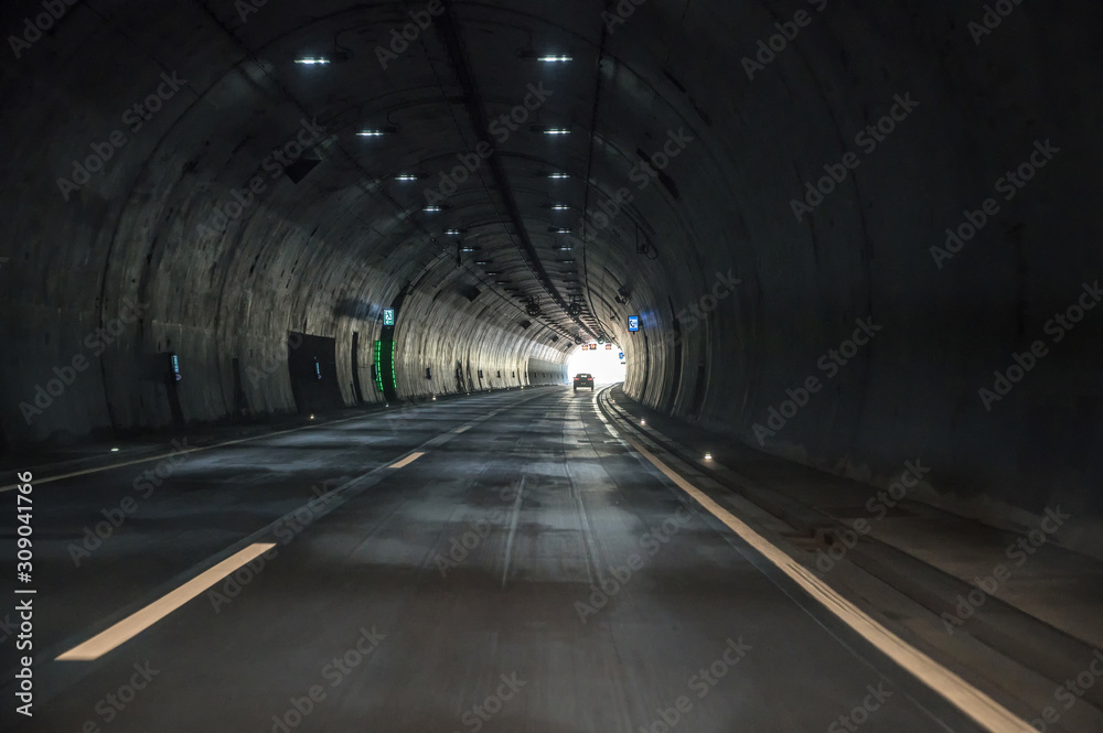 Fahrt durch einen dunklen Tunnel einer Autobahn mit Sicht auf das Licht am Ende des Tunnels