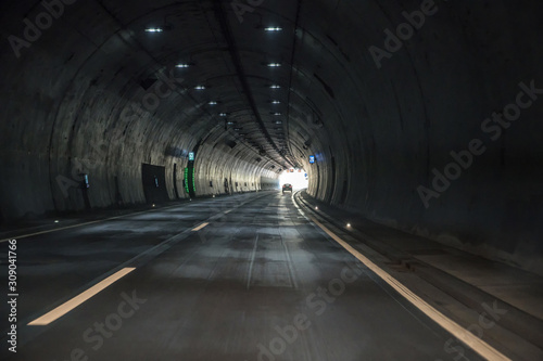 Fototapeta Fahrt durch einen dunklen Tunnel einer Autobahn mit Sicht auf das Licht am Ende des Tunnels