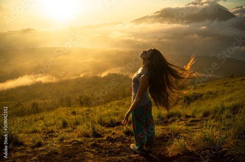 Beautiful girl with long hair on the volcano Batur on the island of Bali. Indonesia at sunrise. A lot of sun