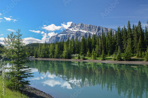 Peak of Mt. Rundle with snow bands reflected in tree lined Cascade Pond in Banff National Park, Alberta, Canada © Robert W. Coffen