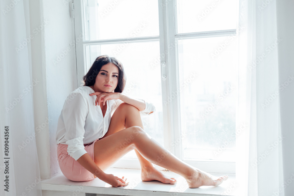 girl sits at a window in a white room