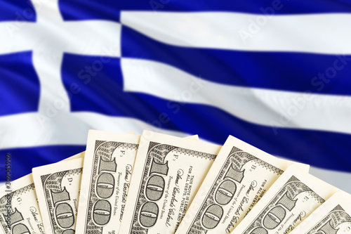 Greece economy concept. Dollar banknotes on the side of national flag with waving background. Financial theme.