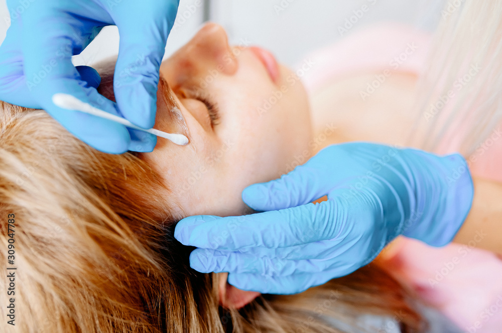 Young woman shapes her eyebrows with eyebrow pencil Young woman shapes her eyebrows with eyebrow pencil