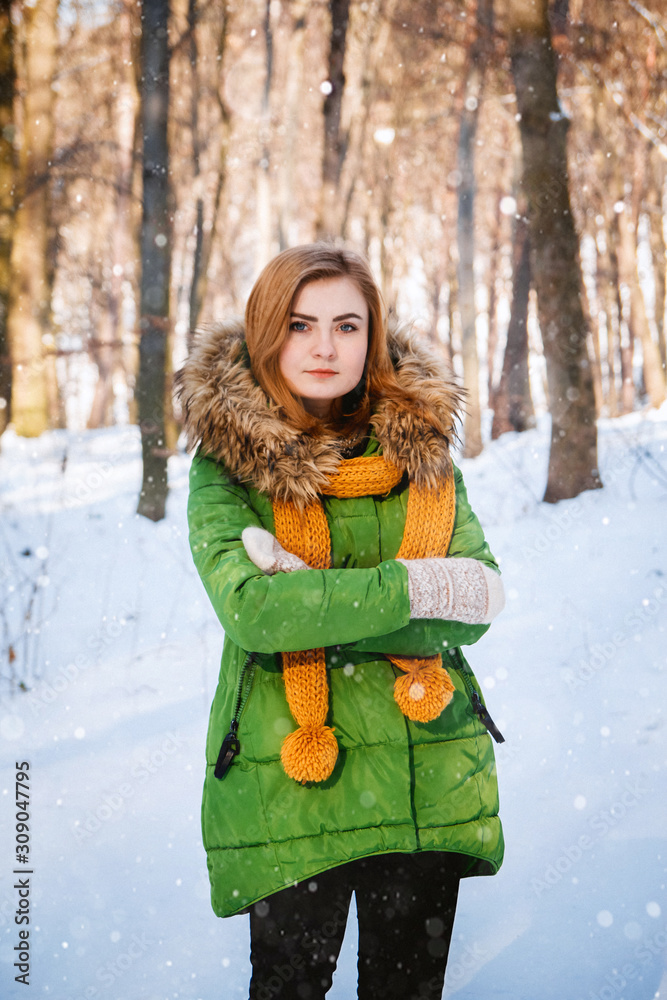 Beautiful young girl in a winter forest. Winter portrait of women dressed in mittens and scarf. Place for text or advertising Beautiful young girl in a winter forest. Winter portrait of women dressed in mittens and scarf. Place for text or advertising