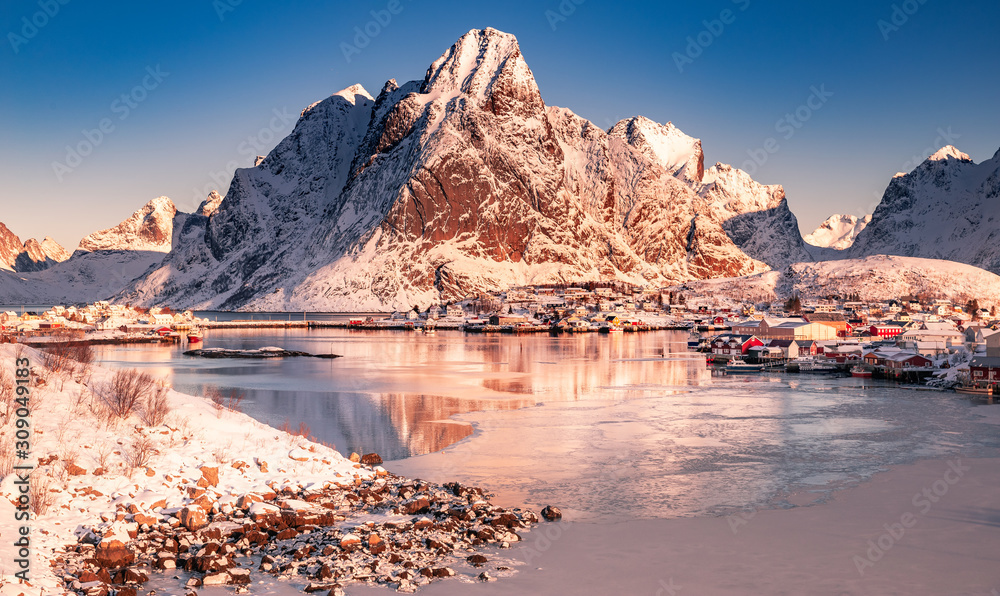 Amazing aerial view of Lofoten Islands nature from drone, winter sunrise snowy scenery of village Reine, Sakrisoy and Hamnoy during beautiful mountain ridge with alpenglow, scene over polar circle.