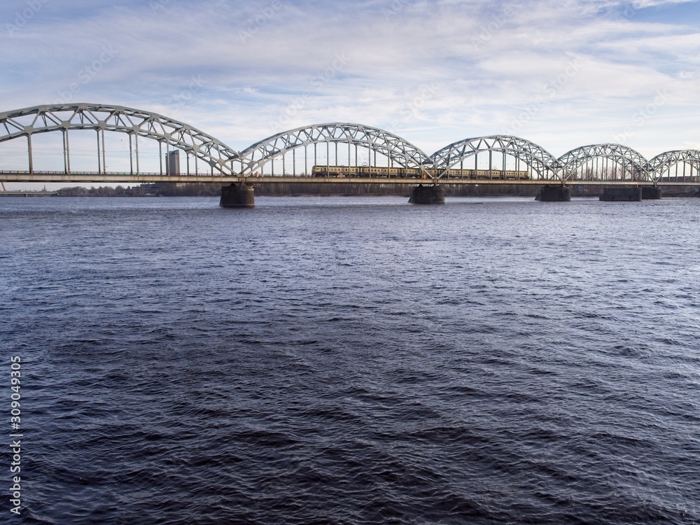 Naklejka premium A train is crossing the Daugav River heading to Riga Central Station on a cold day in March 2018