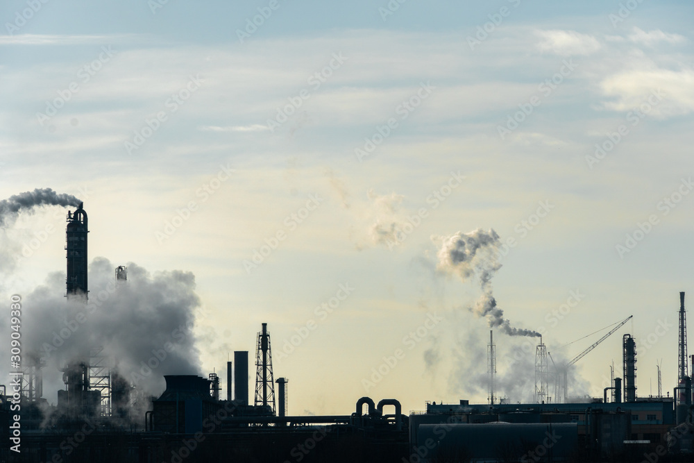 Chemical industry. Environmental pollution by harmful emissions into the atmosphere. Poisonous smoke comes from the big pipes. The factory poisons nature. Silhouette of pipes and smoke. Sunny day.