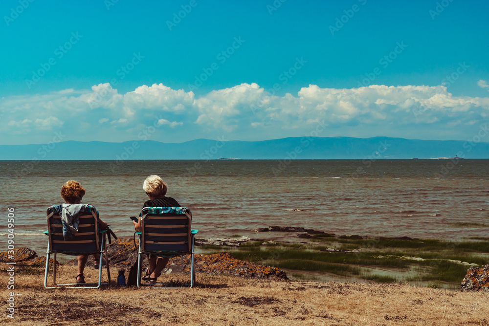 Ladies sitting at the water's edge looking at the horizon