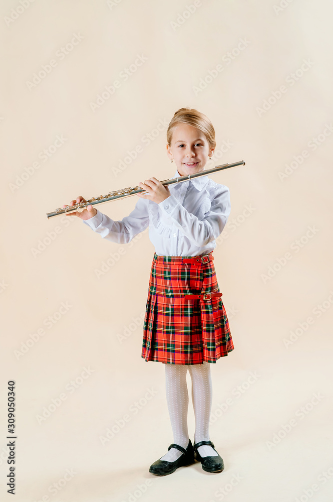 Little girl 10 in a white shirt with a flute in her hands looks into the lens and smiles Little girl 10 in a white shirt with a flute in her hands looks into the lens and smiles