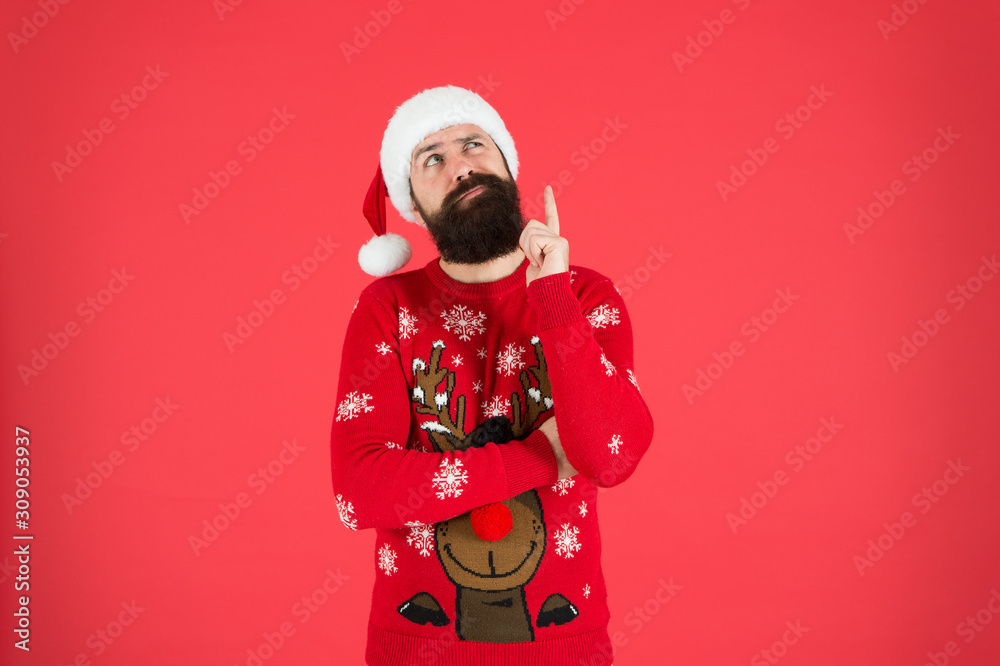 Winter fashion. Guy wearing winter clothes accessory. Bearded Santa claus red background. Something on his mind. Winter holidays. Man bearded hipster wear winter knitted hat. Barbershop facial hair