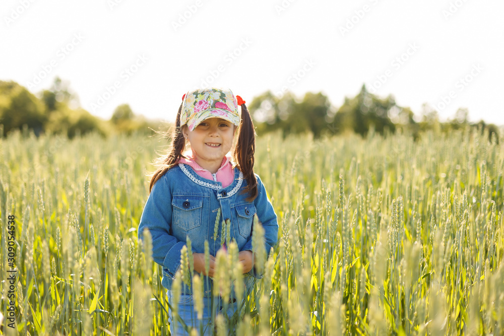 Happy little girl in the middle of a field of spikelets with blue cloudy sky background Happy little girl in the middle of a field of spikelets with blue cloudy sky background