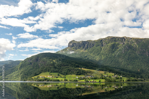 Scandinavian perfect landscape. Norwegian landscape with a fjord, mountains and a village. Summer idealistic landscape. Village by the sea.