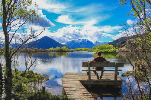 Young man is sitting next to Glenorchy Lagoon in Glenorchy, South Island, New Zealand