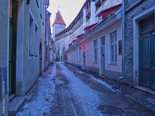 Narrow Alleyway in the medieval old town of Tallinn at dusk with a tower of the city wall in the background